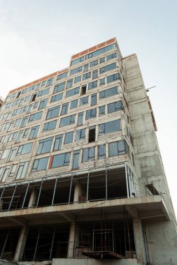 Mavi gökyüzünün arka planında yapım aşamasındaki çok katlı bir bina ve vinç.