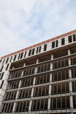 Mavi gökyüzünün arka planında yapım aşamasındaki çok katlı bir bina ve vinç.