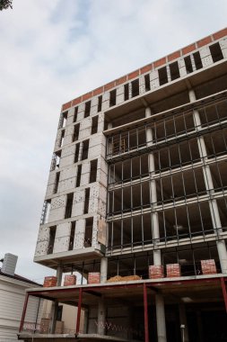 Mavi gökyüzünün arka planında yapım aşamasındaki çok katlı bir bina ve vinç.