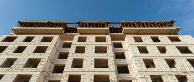 Mavi gökyüzünün arka planında inşaat halindeki çok katlı bir bina ve vinç manzarası