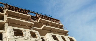 Mavi gökyüzünün arka planında inşaat halindeki çok katlı bir bina ve vinç manzarası