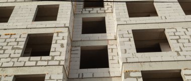 Mavi gökyüzünün arka planında inşaat halindeki çok katlı bir bina ve vinç manzarası