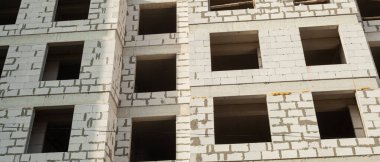 Mavi gökyüzünün arka planında inşaat halindeki çok katlı bir bina ve vinç manzarası