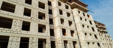 Mavi gökyüzünün arka planında inşaat halindeki çok katlı bir bina ve vinç manzarası