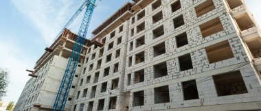 Mavi gökyüzünün arka planında inşaat halindeki çok katlı bir bina ve vinç manzarası