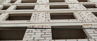 Mavi gökyüzünün arka planında inşaat halindeki çok katlı bir bina ve vinç manzarası