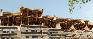 Mavi gökyüzünün arka planında inşaat halindeki çok katlı bir bina ve vinç manzarası