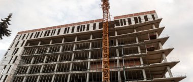 Mavi gökyüzünün arka planında inşaat halindeki çok katlı bir bina ve vinç manzarası