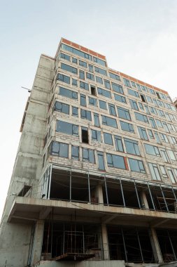 Mavi gökyüzünün arka planında yapım aşamasındaki çok katlı bir bina ve vinç.