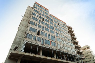 Mavi gökyüzünün arka planında yapım aşamasındaki çok katlı bir bina ve vinç.
