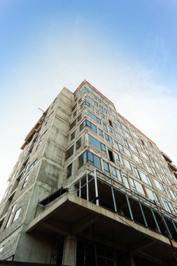 Mavi gökyüzünün arka planında yapım aşamasındaki çok katlı bir bina ve vinç.