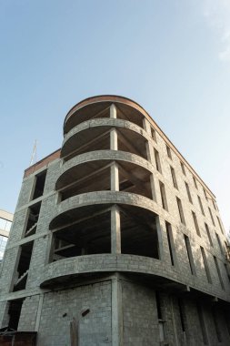 Mavi gökyüzünün arka planında yapım aşamasındaki çok katlı bir bina ve vinç.