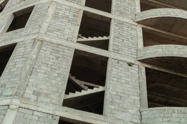 Mavi gökyüzünün arka planında yapım aşamasındaki çok katlı bir bina ve vinç.