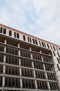 Mavi gökyüzünün arka planında yapım aşamasındaki çok katlı bir bina ve vinç.