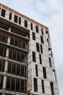 Mavi gökyüzünün arka planında yapım aşamasındaki çok katlı bir bina ve vinç.