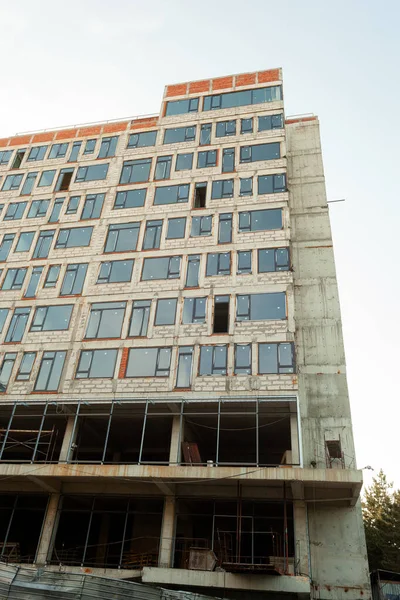 Mavi gökyüzünün arka planında yapım aşamasındaki çok katlı bir bina ve vinç.