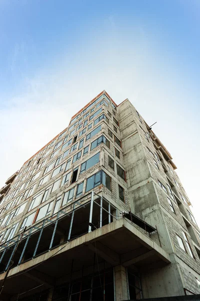 Mavi gökyüzünün arka planında yapım aşamasındaki çok katlı bir bina ve vinç.