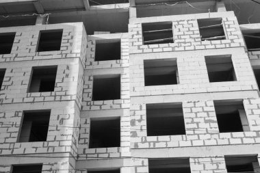 Mavi gökyüzünün arka planında yapım aşamasında olan çok katlı bir binanın siyah beyaz fotoğrafı.