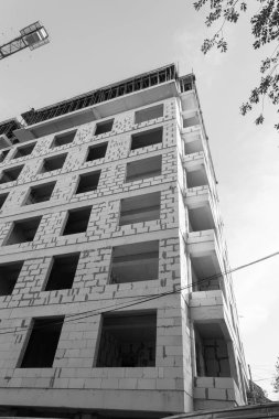 Mavi gökyüzünün arka planında yapım aşamasında olan çok katlı bir binanın siyah beyaz fotoğrafı.