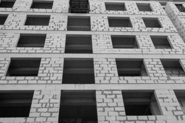 Mavi gökyüzünün arka planında yapım aşamasında olan çok katlı bir binanın siyah beyaz fotoğrafı.