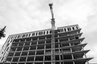 Mavi gökyüzünün arka planında yapım aşamasında olan çok katlı bir binanın siyah beyaz fotoğrafı.