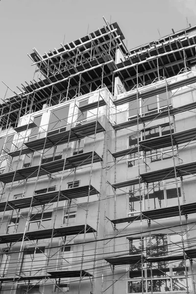 青空を背景に建設中の複数階建ての住宅やクレーンの白と黒の写真 — ストック写真