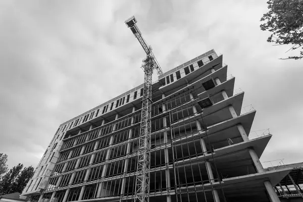Mavi gökyüzünün arka planında yapım aşamasında olan çok katlı bir binanın siyah beyaz fotoğrafı.