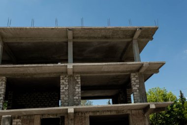 Mavi gökyüzünün arka planında yapım aşamasındaki çok katlı bir bina ve vinç.