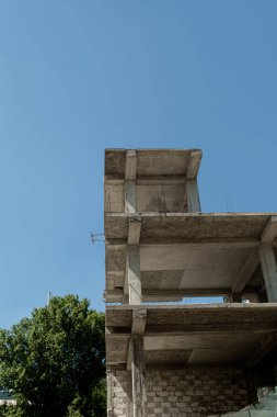 Mavi gökyüzünün arka planında yapım aşamasındaki çok katlı bir bina ve vinç.