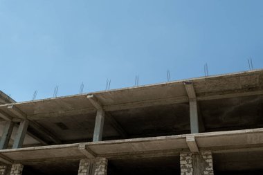 Mavi gökyüzünün arka planında yapım aşamasındaki çok katlı bir bina ve vinç.