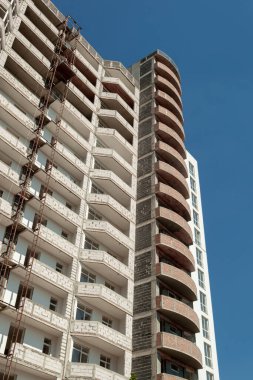 Mavi gökyüzünün arka planında yapım aşamasındaki çok katlı bir bina ve vinç.