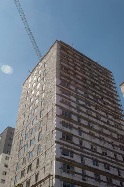 Mavi gökyüzünün arka planında yapım aşamasındaki çok katlı bir bina ve vinç.