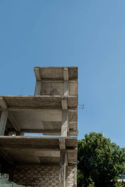 Mavi gökyüzünün arka planında yapım aşamasındaki çok katlı bir bina ve vinç.