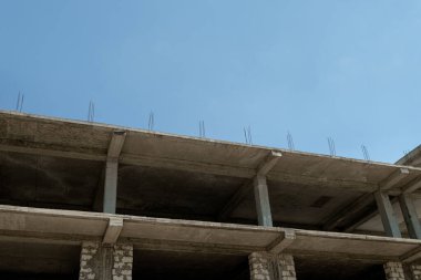 Mavi gökyüzünün arka planında yapım aşamasındaki çok katlı bir bina ve vinç.