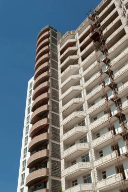 Mavi gökyüzünün arka planında yapım aşamasındaki çok katlı bir bina ve vinç.