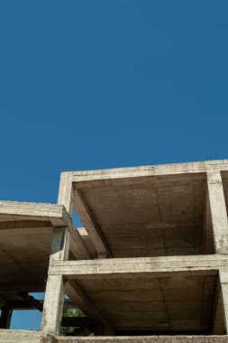 Mavi gökyüzünün arka planında yapım aşamasındaki çok katlı bir bina ve vinç.