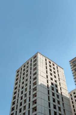 Mavi gökyüzünün arka planında yapım aşamasındaki çok katlı bir bina ve vinç.