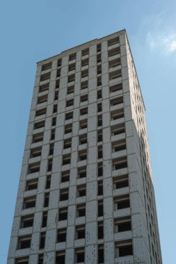 Mavi gökyüzünün arka planında yapım aşamasındaki çok katlı bir bina ve vinç.