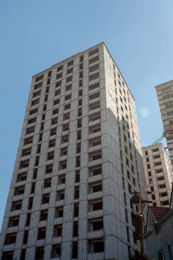 Mavi gökyüzünün arka planında yapım aşamasındaki çok katlı bir bina ve vinç.