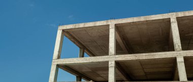 Mavi gökyüzünün arka planında inşaat halindeki çok katlı bir bina ve vinç manzarası