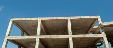 Mavi gökyüzünün arka planında inşaat halindeki çok katlı bir bina ve vinç manzarası