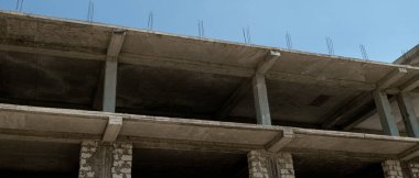 Mavi gökyüzünün arka planında inşaat halindeki çok katlı bir bina ve vinç manzarası
