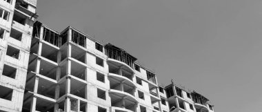 Mavi gökyüzünün arka planında yapım aşamasında olan çok katlı bir binanın siyah beyaz manzarası.