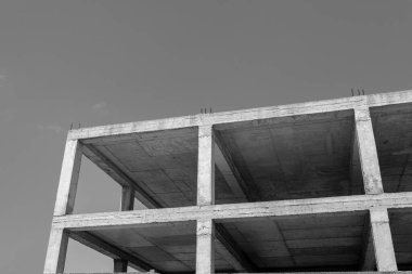 Mavi gökyüzünün arka planında yapım aşamasında olan çok katlı bir binanın siyah beyaz fotoğrafı.