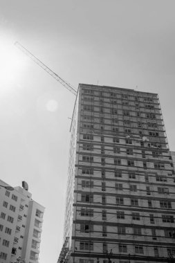 Mavi gökyüzünün arka planında yapım aşamasında olan çok katlı bir binanın siyah beyaz fotoğrafı.