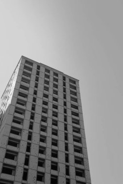 Mavi gökyüzünün arka planında yapım aşamasında olan çok katlı bir binanın siyah beyaz fotoğrafı.