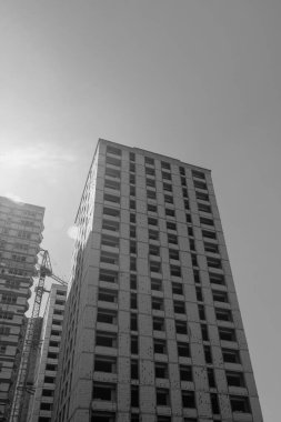 Mavi gökyüzünün arka planında yapım aşamasında olan çok katlı bir binanın siyah beyaz fotoğrafı.