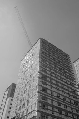 Mavi gökyüzünün arka planında yapım aşamasında olan çok katlı bir binanın siyah beyaz fotoğrafı.