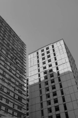 Mavi gökyüzünün arka planında yapım aşamasında olan çok katlı bir binanın siyah beyaz fotoğrafı.