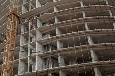 Mavi gökyüzünün arka planında yapım aşamasındaki çok katlı bir bina ve vinç.